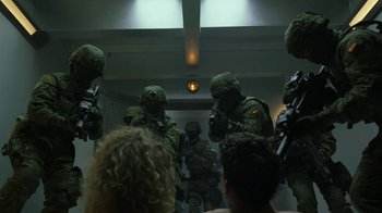 Movie still from “Money Heist” (2017), created by Álex Pina – A group of people in military uniforms standing in a room; Wide shot, Over the shoulder angle