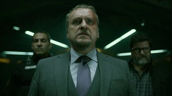 Movie still from “Money Heist” (2017), created by Álex Pina – A person wearing a suit and a tie; Medium shot, Low angle