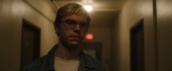 Movie still from “Monster” (2022), directed by Clement Virgo – A man wearing glasses standing in a hallway; Close Up shot, Over the shoulder angle
