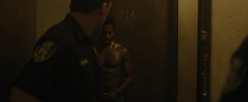 Movie still from “Monster” (2022), directed by Clement Virgo – A man standing next to a door way; Medium shot, Over the shoulder angle