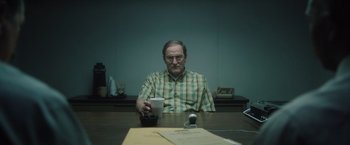 Movie still from “Monster” (2022), directed by Clement Virgo – An older man sitting at a table holding a coffee cup; Medium shot, Over the shoulder angle