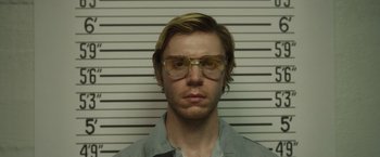 Movie still from “Monster” (2022), directed by Clement Virgo – A man with blonde hair wearing glasses and a gray shirt; Close Up shot, Low angle