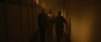Movie still from “Monster” (2022), directed by Clement Virgo – A group of police officers walking down a hallway; Wide shot, Low angle