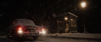 Movie still from “Monster” (2022), directed by Clement Virgo – A person sitting at a bus stop on a snowy night; Extreme Wide shot, Over the shoulder angle