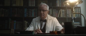 Movie still from “Monster” (2022), directed by Clement Virgo – An older man sitting at a table in a library; Medium shot, Low angle