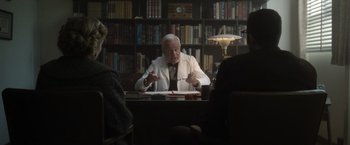 Movie still from “Monster” (2022), directed by Clement Virgo – An older man sitting at a table in a library; Medium shot, Over the shoulder angle