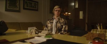 Movie still from “Monster” (2022), directed by Clement Virgo – A man sitting at a table in front of a laptop; Medium shot, Low angle