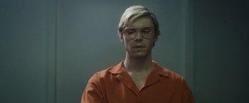 Movie still from “Monster” (2022), directed by Clement Virgo – A man with blonde hair wearing glasses and an orange shirt; Close Up shot, Low angle