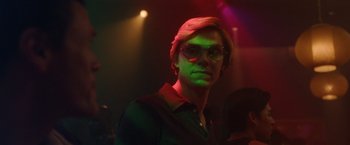 Movie still from “Monster” (2022), directed by Clement Virgo – A man in a green light with glasses on; Close Up shot, Low angle