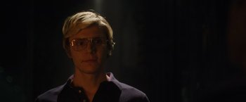 Movie still from “Monster” (2022), directed by Clement Virgo – A man with blonde hair wearing glasses in a dark room; Close Up shot, Over the shoulder angle