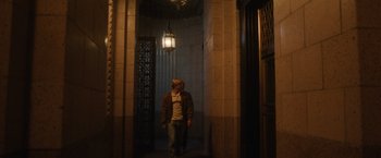 Movie still from “Monster” (2022), directed by Clement Virgo – A man is walking in a hallway at night; Wide shot, Low angle