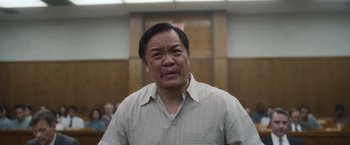Movie still from “Monster” (2022), directed by Clement Virgo – An older man in a white shirt is in a courtroom; Close Up shot, Low angle
