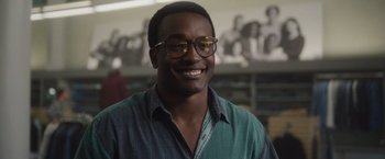 Movie still from “Monster” (2022), directed by Clement Virgo – A man wearing glasses and smiling for the camera; Close Up shot, Low angle
