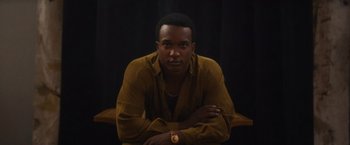 Movie still from “Monster” (2022), directed by Clement Virgo – A man sitting on top of a wooden bench; Close Up shot, Low angle