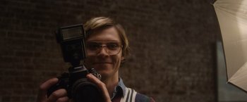 Movie still from “Monster” (2022), directed by Clement Virgo – A man holding up a camera in front of a brick wall; Close Up shot, Low angle