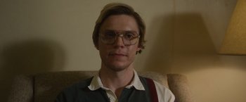 Movie still from “Monster” (2022), directed by Clement Virgo – A person wearing glasses on a couch; Close Up shot, Low angle