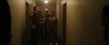 Movie still from “Monster” (2022), directed by Clement Virgo – A group of men standing in a hallway; Medium shot, Over the shoulder angle
