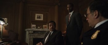 Movie still from “Monster” (2022), directed by Clement Virgo – Two men in suits and ties sitting in a room; Medium shot, Low angle