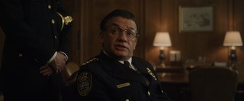 Movie still from “Monster” (2022), directed by Clement Virgo – A man in a police uniform sitting in front of a lamp; Close Up shot, Over the shoulder angle