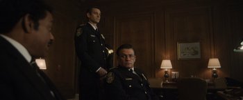 Movie still from “Monster” (2022), directed by Clement Virgo – Two police officers in uniform sitting in a room; Medium shot, Low angle