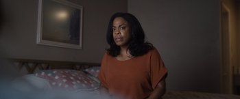Movie still from “Monster” (2022), directed by Clement Virgo – A woman sitting on a bed in a room; Close Up shot, Over the shoulder angle