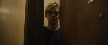 Movie still from “Monster” (2022), directed by Clement Virgo – A man wearing glasses standing in front of a door; Close Up shot, Low angle