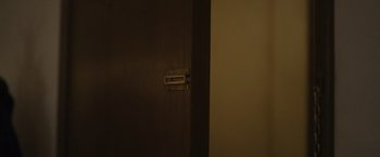 Movie still from “Monster” (2022), directed by Clement Virgo – The door of the room is closed with a metal hinge on it; Extreme Close Up shot, High angle