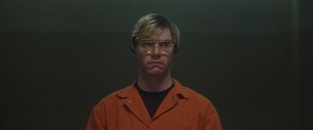 Movie still from “Monster” (2022), directed by Clement Virgo – A man in an orange shirt wearing glasses; Close Up shot, Low angle