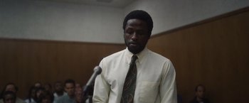 Movie still from “Monster” (2022), directed by Clement Virgo – A man in a white dress shirt and a tie; Close Up shot, Low angle