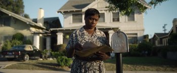 Movie still from “Monster” (2022), directed by Clement Virgo – A woman standing in front of a us mail box; Medium shot, Low angle