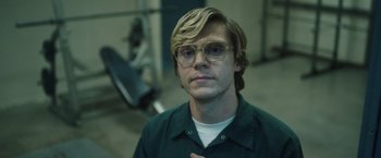 Movie still from “Monster” (2022), directed by Clement Virgo – A man with blonde hair and glasses in a room; Close Up shot, Low angle