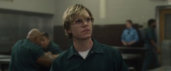 Movie still from “Monster” (2022), directed by Clement Virgo – A man with blonde hair wearing glasses and a green shirt; Close Up shot, Over the shoulder angle
