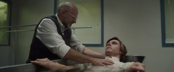 Movie still from “Monster” (2022), directed by Clement Virgo – An older man and a younger man are touching each other; Medium shot, Low angle