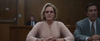 Movie still from “Monster” (2022), directed by Clement Virgo – An older woman in a pink dress sitting in a courtroom; Close Up shot, Low angle