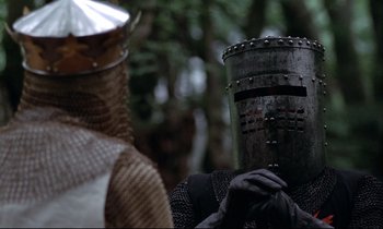 Movie still from “Monty Python and the Holy Grail” (1975), directed by Terry Gilliam – A person wearing a helmet and holding a sword; Close Up shot, Low angle