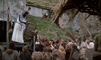 Movie still from “Monty Python and the Holy Grail” (1975), directed by Terry Gilliam – A group of people standing next to each other near a building; Wide shot, Low angle