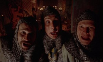 Movie still from “Monty Python and the Holy Grail” (1975), directed by Terry Gilliam – A group of men wearing chainmail and a white shirt; Medium shot, Low angle