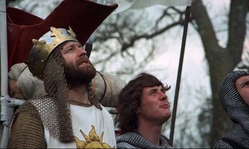 Movie still from “Monty Python and the Holy Grail” (1975), directed by Terry Gilliam – Two men dressed in medieval costumes and holding umbrellas; Medium shot, Low angle
