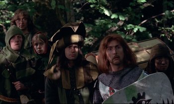 Movie still from “Monty Python and the Holy Grail” (1975), directed by Terry Gilliam – A group of people dressed up in costumes; Medium shot, High angle