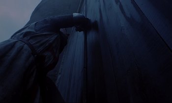 Movie still from “Monty Python and the Holy Grail” (1975), directed by Terry Gilliam – A man is painting a wall with a paint roller; Medium shot, Low angle