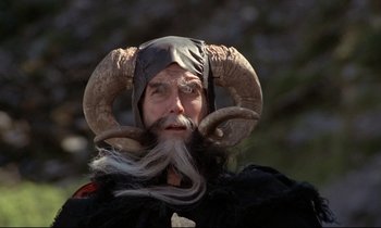 Movie still from “Monty Python and the Holy Grail” (1975), directed by Terry Gilliam – A man with a long beard wearing a horned hat; Close Up shot, Low angle