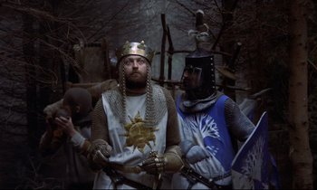 Movie still from “Monty Python and the Holy Grail” (1975), directed by Terry Gilliam – Two men dressed as medieval knights standing next to each other; Medium shot, High angle