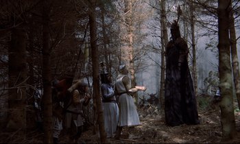 Movie still from “Monty Python and the Holy Grail” (1975), directed by Terry Gilliam – A group of people dressed in medieval clothing in the woods; Wide shot, Low angle
