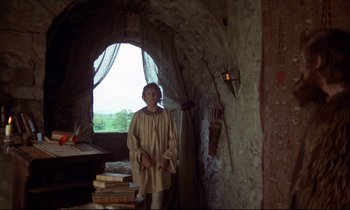 Movie still from “Monty Python and the Holy Grail” (1975), directed by Terry Gilliam – A man standing inside of an old stone building; Wide shot, Low angle