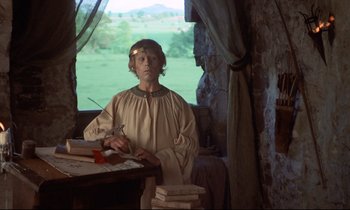 Movie still from “Monty Python and the Holy Grail” (1975), directed by Terry Gilliam – A young man in medieval garb standing in front of a window; Medium shot, High angle