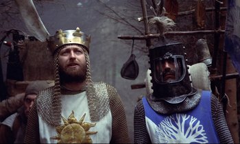 Movie still from “Monty Python and the Holy Grail” (1975), directed by Terry Gilliam – Two men dressed as medieval knights standing next to each other; Medium shot, Low angle