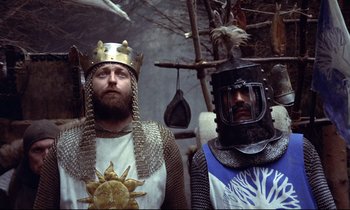 Movie still from “Monty Python and the Holy Grail” (1975), directed by Terry Gilliam – Two men dressed as medieval knights standing next to each other; Medium shot, Low angle
