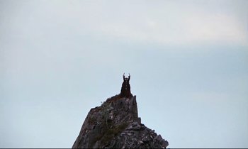 Movie still from “Monty Python and the Holy Grail” (1975), directed by Terry Gilliam – A goat standing on top of a mountain; Extreme Wide shot, Low angle