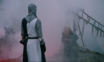 Movie still from “Monty Python and the Holy Grail” (1975), directed by Terry Gilliam – A man in medieval garb is standing in front of a woman; Wide shot, Over the shoulder angle