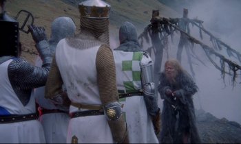 Movie still from “Monty Python and the Holy Grail” (1975), directed by Terry Gilliam – A group of people dressed in medieval clothing; Wide shot, High angle